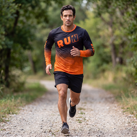 Male runner jogging outdoors in a black and orange RUN REST LIFT REPEAT long sleeve running shirt