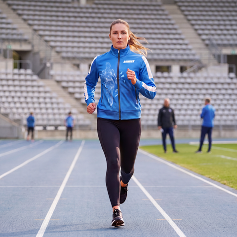 Women's Running Track Jacket in blue worn by female athlete running on a collegiate track